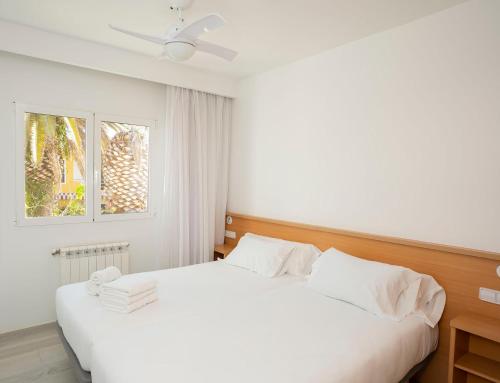 a bedroom with a white bed and a window at Apartamentos Tamarindos Peñiscola in Peñíscola