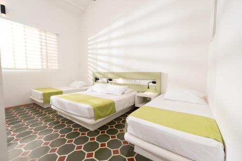 a bedroom with two beds and a window at Hotel Las Palmeras in Villeta