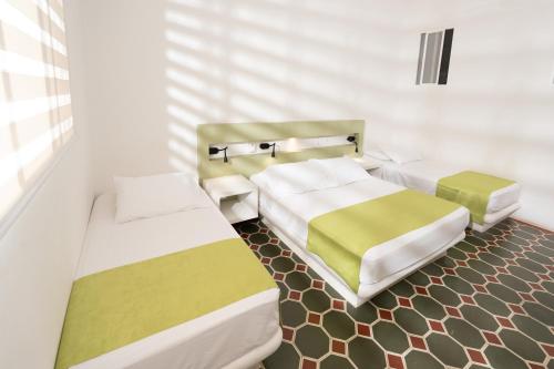 two beds in a small room with at Hotel Las Palmeras in Villeta