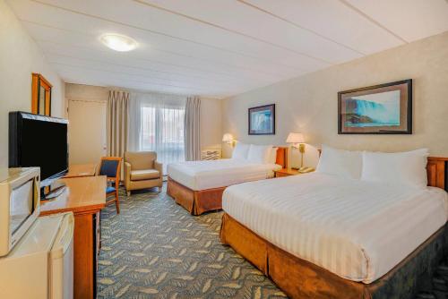 a hotel room with two beds and a flat screen tv at Travelodge by Wyndham Niagara Falls At the Falls in Niagara Falls