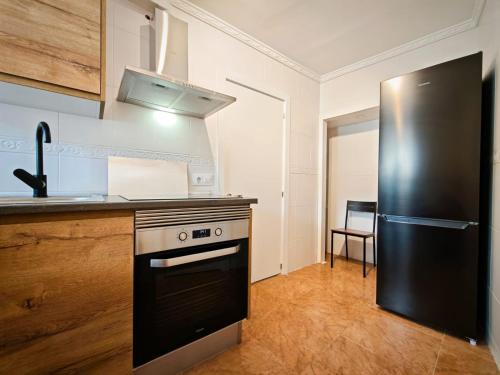 a kitchen with a black stove and a refrigerator at Casa rural El Nido in Constantina