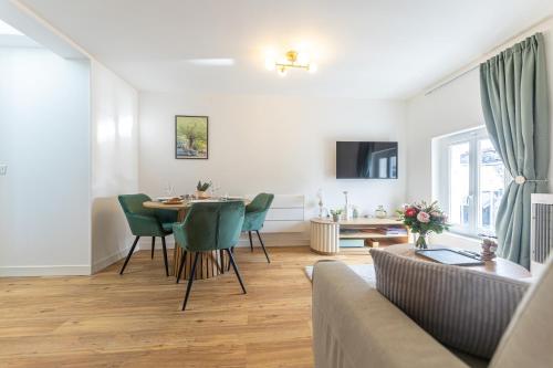 ein Wohnzimmer mit einem Tisch und grünen Stühlen in der Unterkunft Les toits d'Angoulême in Angoulême