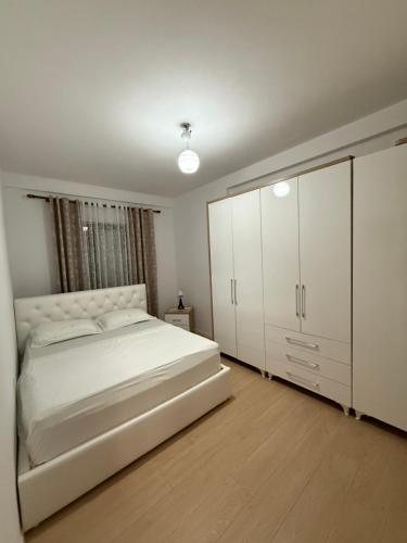 a bedroom with a large white bed and cabinets at Nene Tereza Airport Apartment in Valjiosi