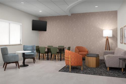 a waiting room with chairs and tables and a tv at Hampton Inn Fayetteville Fort Bragg in Fayetteville
