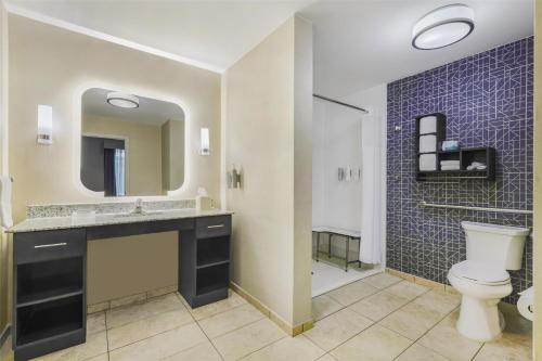 a bathroom with a toilet and a sink and a mirror at Homewood Suites by Hilton Huntsville-Downtown in Huntsville