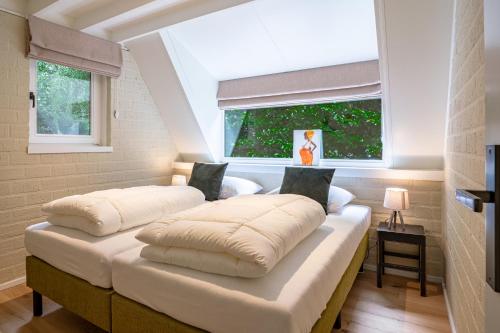 twee bedden in een kamer met een raam bij Boshuisje Rekem - Kitoko in Lanaken