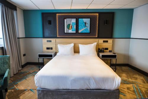 a large bed in a room with two tables at DoubleTree by Hilton Coventry Building Society Arena in Coventry