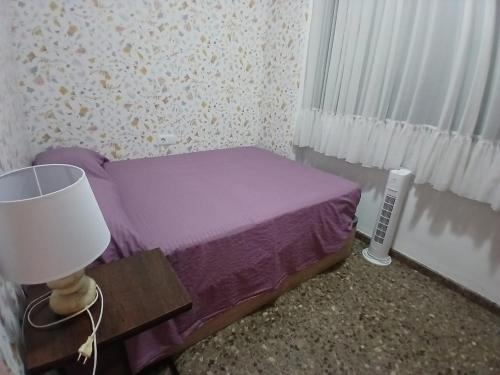 a small purple bed in a room with a lamp at Tikitita House in Gandía