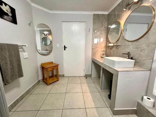 a bathroom with a sink and two mirrors at Pelican Lodge Guesthouse in Sedgefield