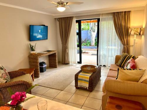 a living room with a couch and a tv at Pelican Lodge Guesthouse in Sedgefield