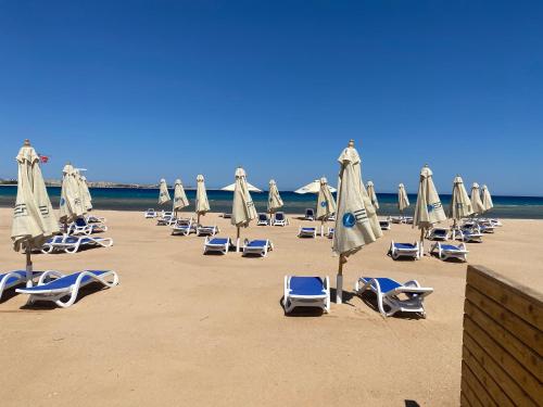 a bunch of lounge chairs and umbrellas on a beach at Cozy studio in Azzurra Resort Sahl Hasheesh 65 Sq M in Hurghada