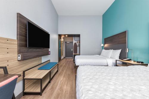 a hotel room with two beds and a flat screen tv at Tru By Hilton The Colony in The Colony