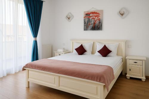 a bedroom with a large white bed with red pillows at Vila Green by Plaiul GreenBike in Deva