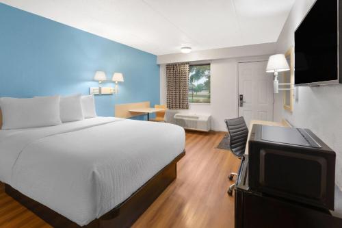 a hotel room with a bed and a television at Travelodge by Wyndham Madison Heights MI in Madison Heights