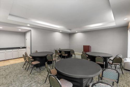 a conference room with tables and chairs and a screen at Wingate by Wyndham Greensboro-Coliseum in Greensboro