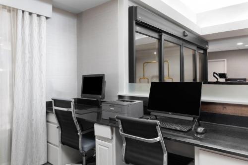 an office with a desk with a computer and chairs at Wingate by Wyndham Greensboro-Coliseum in Greensboro