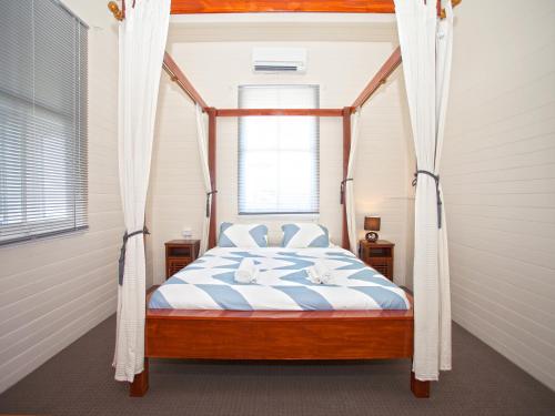 CBD Holiday Home في ماكاي: غرفة نوم مع سرير مظلة مع نافذة