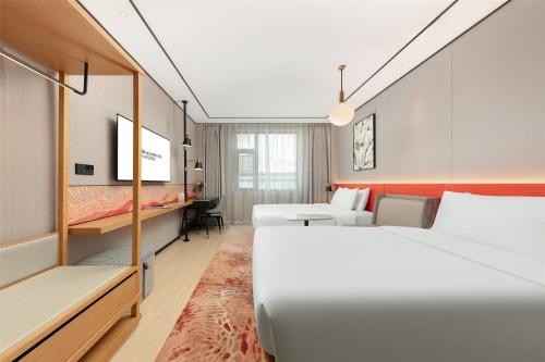 a hotel room with two beds and a couch at Hilton Garden Inn Shanghai Jiading in Shanghai
