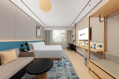 a hotel room with a bed and a couch at Hilton Garden Inn Shanghai Jiading in Shanghai