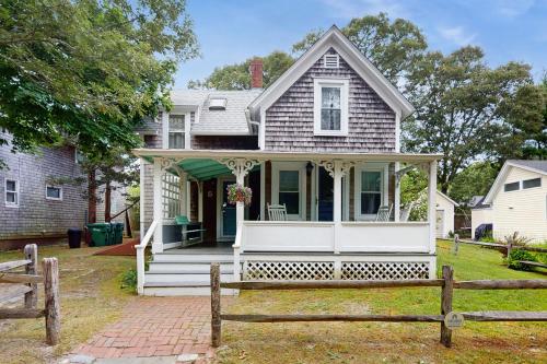 a white house with a porch and a fence at Gingerbread Dream in Oak Bluffs