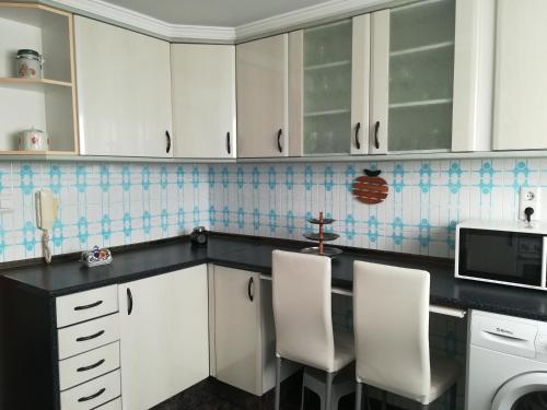 a kitchen with white cabinets and white chairs at Mi playa in Puerto de Sagunto