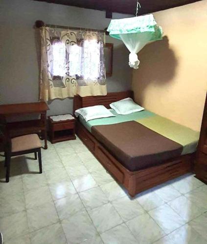a bedroom with a bed and a chair and a window at Maison d'hôtes Villa Mont du Pèlerin à Toamasina Madagascar in Toamasina
