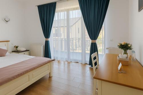 a bedroom with a bed and a desk and a large window at Vila Green by Plaiul GreenBike in Deva