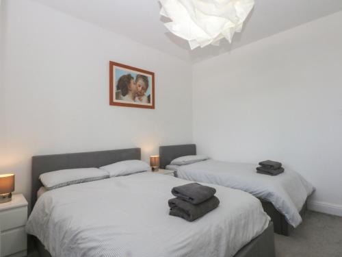 a bedroom with two beds and a chandelier at Cwtch y Môr in Holyhead