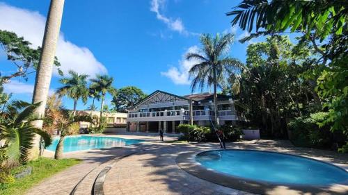a resort with a swimming pool and palm trees at 1BR Tagaytay Condo Staycation near Sky Ranch in Tagaytay