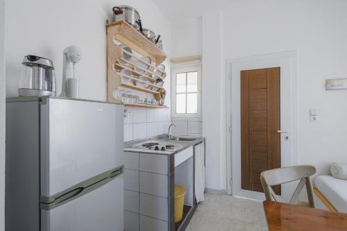 a white kitchen with a refrigerator and a sink at Studios Eliza in Livadion