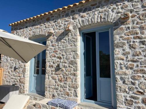 a stone house with blue doors and a patio at Σουίτα ΣΙΚΛΟΣ στο Καραβοστάσι Ν Οιτύλου Μάνης in Karavostasion