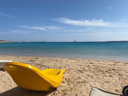 a yellow plastic chair sitting on the beach at Cozy studio in Azzurra Resort Sahl Hasheesh 65 Sq M in Hurghada