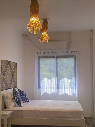 a bedroom with a bed with a window and two lights at Utopia Port Barton in San Vicente