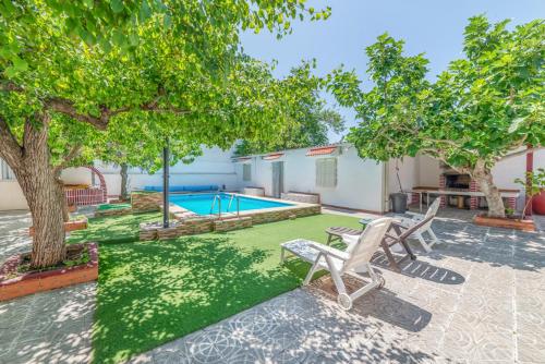 a backyard with a pool and two chairs and trees at El Cortijo de Palma in Villarejo de Salvanés