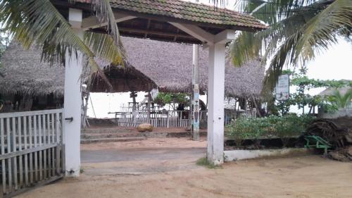 a pavilion with a fence and a palm tree at Mami Beach Resort in Tangalle