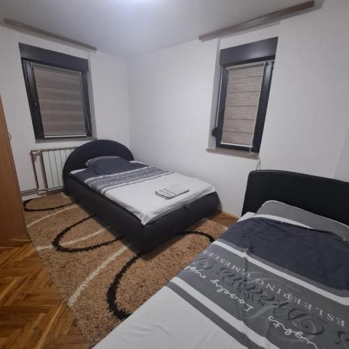 ein Schlafzimmer mit zwei Betten und zwei Fenstern in der Unterkunft Villa Behić in Bihać