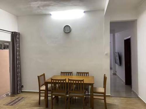a dining room table with chairs and a clock on the wall at Maison de Pagoda in Port Louis