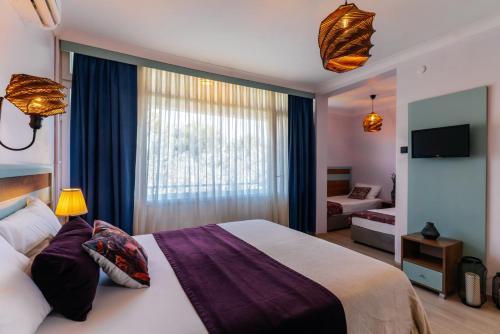ein Hotelzimmer mit einem Bett und einem Fenster in der Unterkunft Palm Beach Hotel in Küçükkuyu