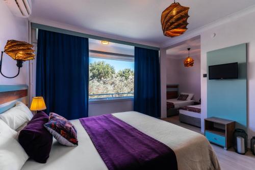 a bedroom with a bed and a large window at Palm Beach Hotel in Kucukkuyu