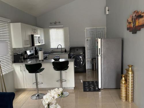 a kitchen with a refrigerator and two bar stools at Cheerful two bedroom home close to mall and Hellshire beach in Portmore