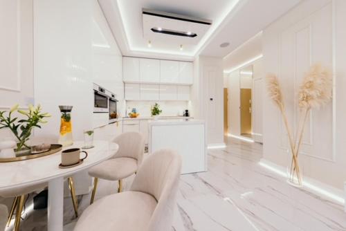 a white kitchen with a table and chairs at Sea Shell Stadium Brzeźno Beach in Gdańsk