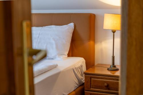 a bedroom with a bed and a lamp on a night stand at Friskó Panzió in Zalakaros