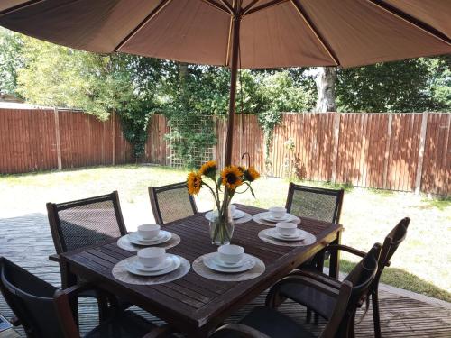 a wooden table with a vase of flowers and an umbrella at 3 Bedroom house, Smart TV, PARKING 3 cars, GARDEN, Wi-fi, CONTRACTOR STAY, close to the Beach, Shops, Hospital, Airport in Bournemouth