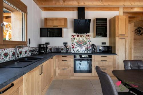 une cuisine avec des placards en bois et des comptoirs noirs dans l'établissement Le Domaine des Fleurs - Chalet Le Coeur de Marie, à Gérardmer