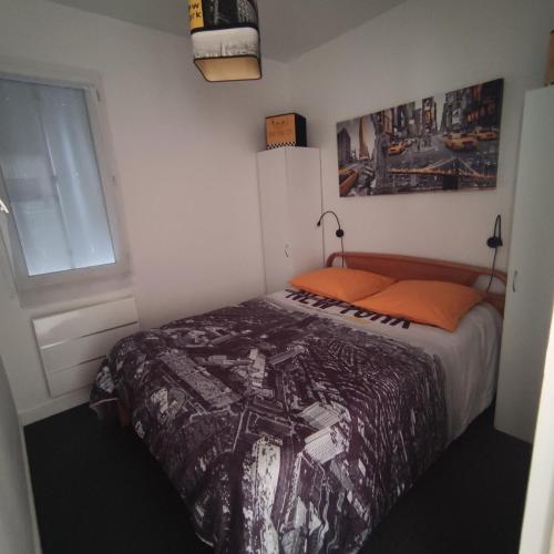 - une chambre avec un lit doté d'un oreiller orange et d'une fenêtre dans l'établissement Loc'Eric, à Pont-lʼAbbé
