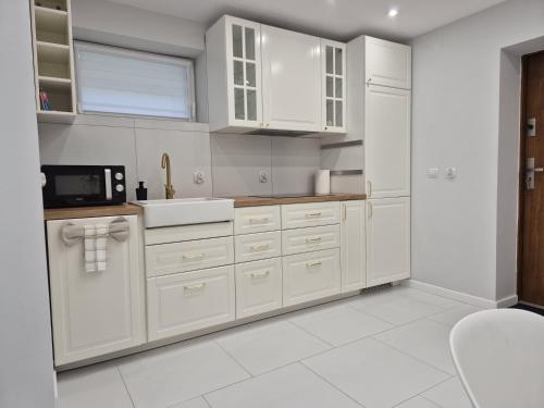 a kitchen with white cabinets and a sink at NEW STORY Apartment in Sława
