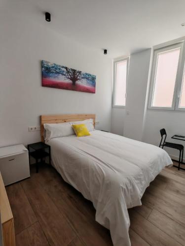 a bedroom with a large white bed with a yellow pillow at Bilbao ROOMS & KITCHEN Rekalde in Bilbao