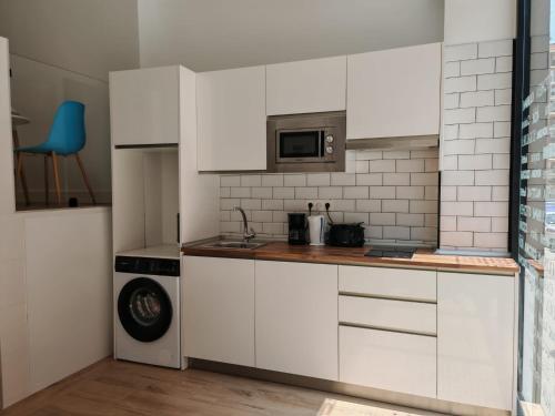a kitchen with white cabinets and a microwave at Bilbao ROOMS & KITCHEN Rekalde in Bilbao
