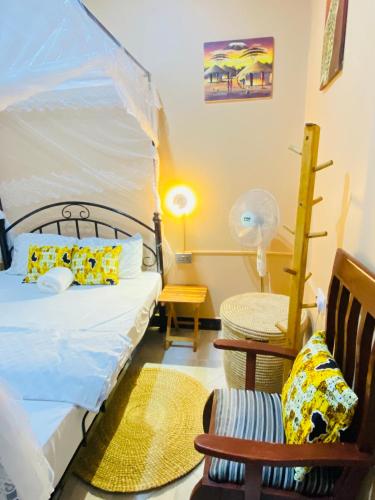 a bedroom with a bed and a chair and a lamp at Shambani House in Arusha