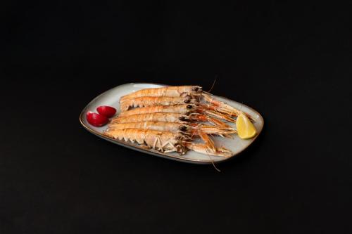 a plate of fish with lemon and two cherries at Hotel Marina in Fažana